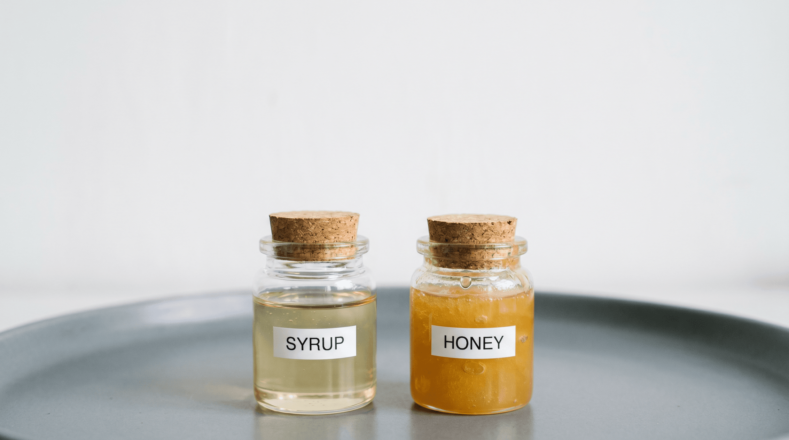 Two small jars labeled syrup and honey.
